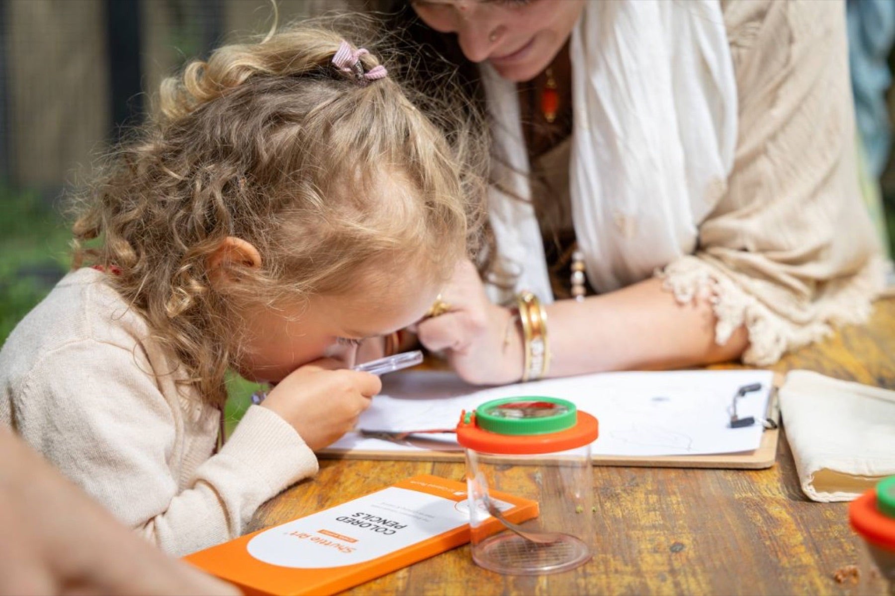 A young child studying nature with a magnifying viewer